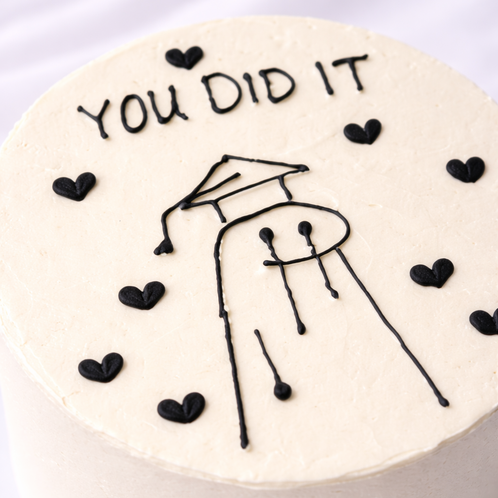 Graduation-themed cake with 'You Did It' text and a stick figure wearing a cap on a white background
