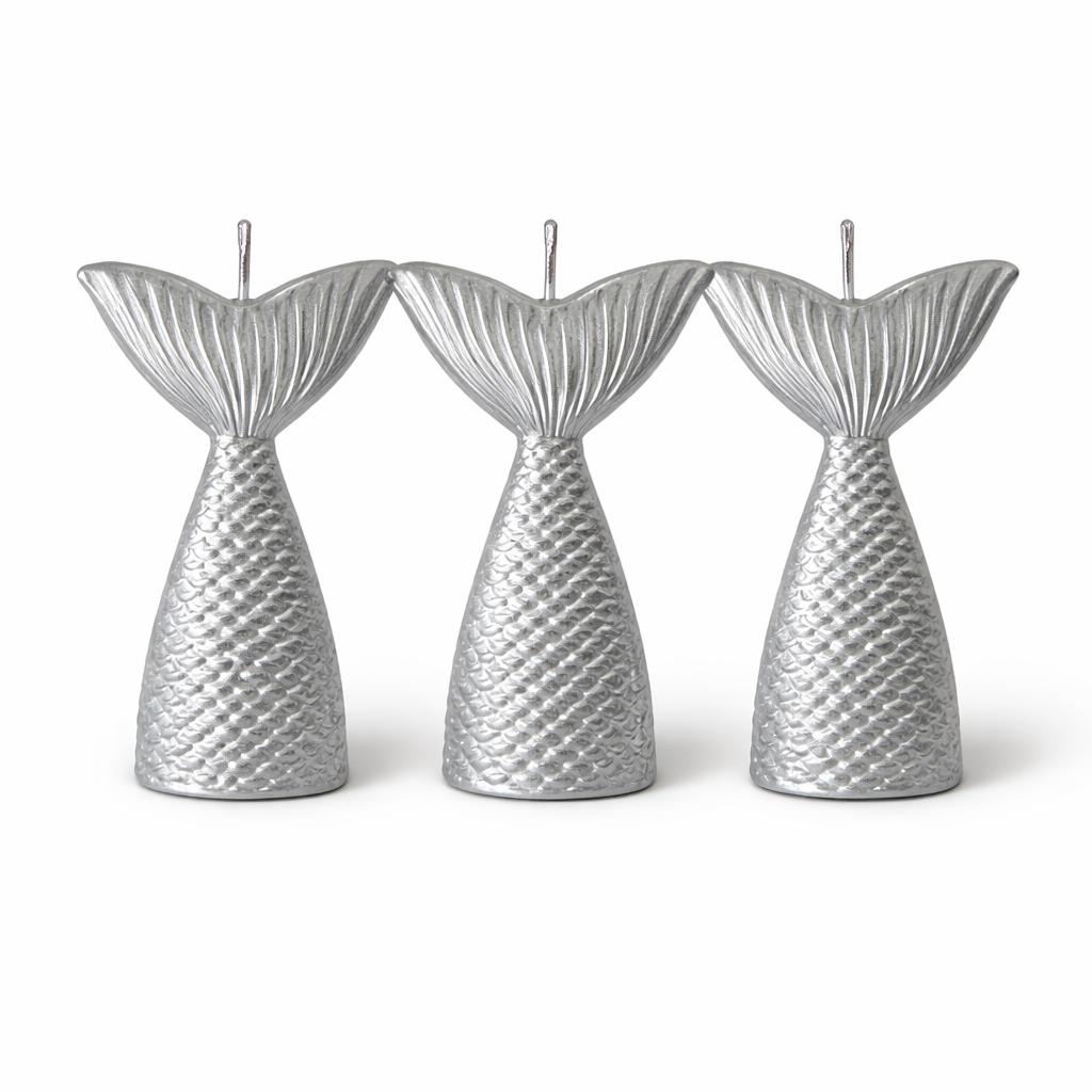 Three silver mermaid tail candles on a white background