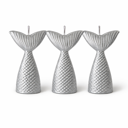 Three silver mermaid tail candles on a white background