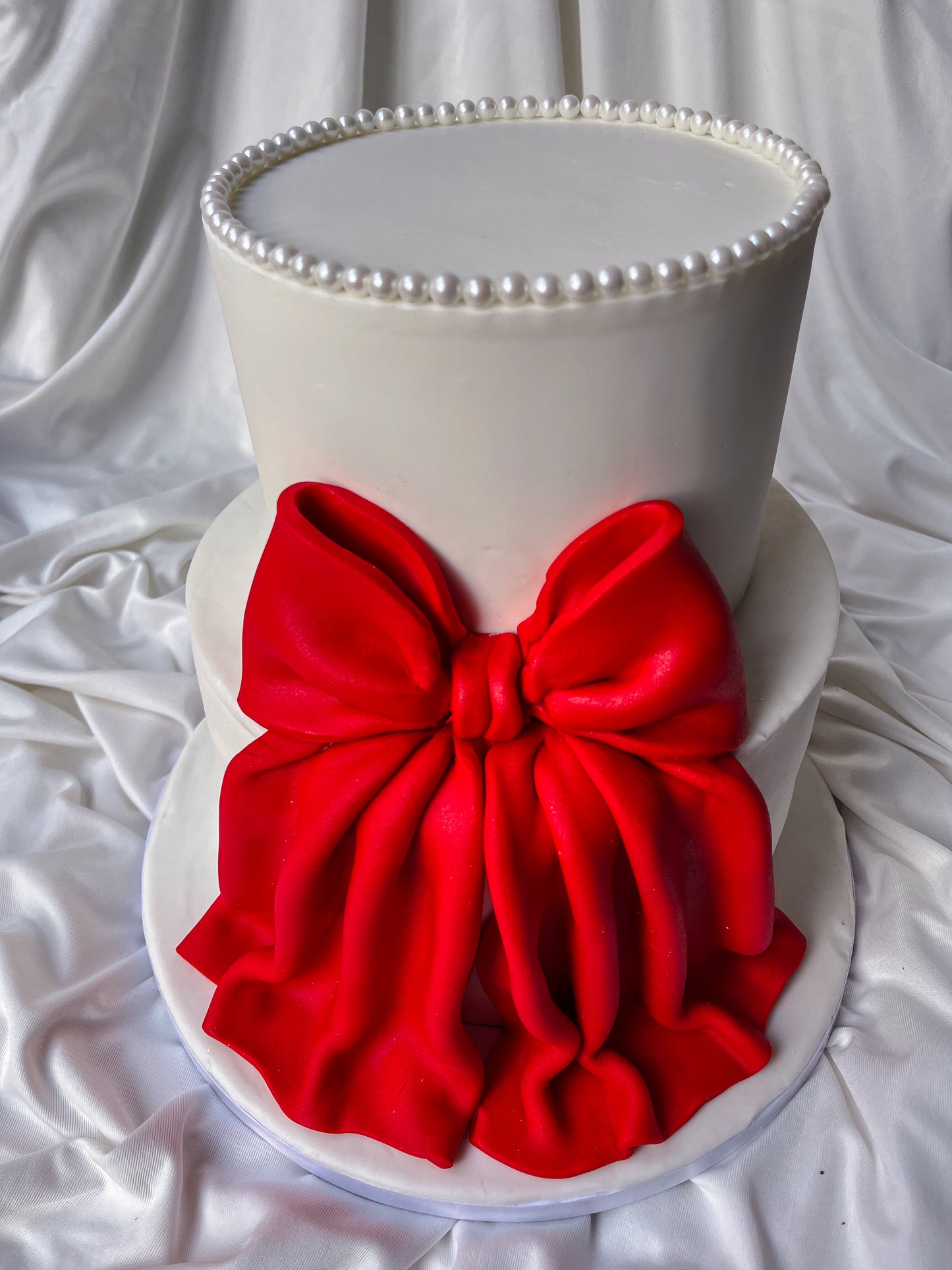 Two-tiered cake with a large red bow on a white background
