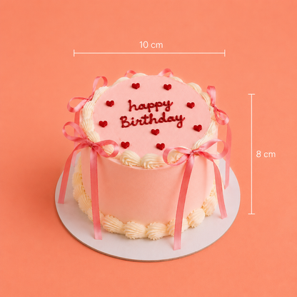 A pink frosted birthday cake with red heart decorations and 'happy Birthday' written on top, shown on a white round board against a peach background with dimension lines indicating 10 cm width and 8 cm height.