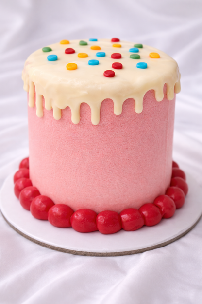Colorful cake with pink base, white cream, and multicolored candies on a white background