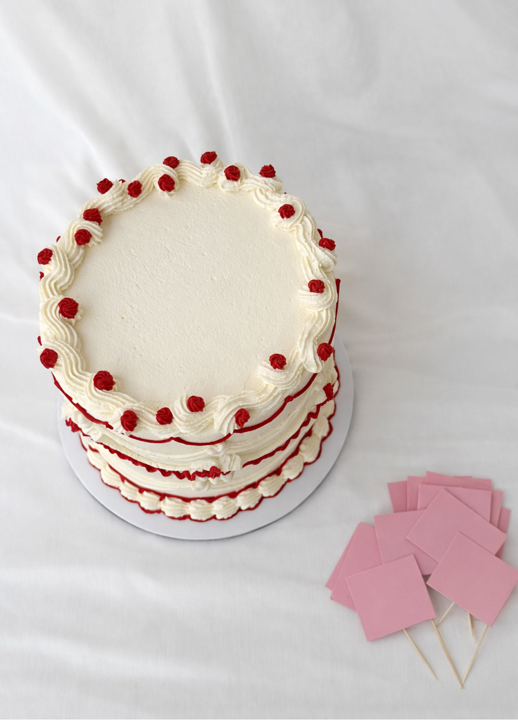 Cake with red decoration on a white background, accompanied by pink paper flags!