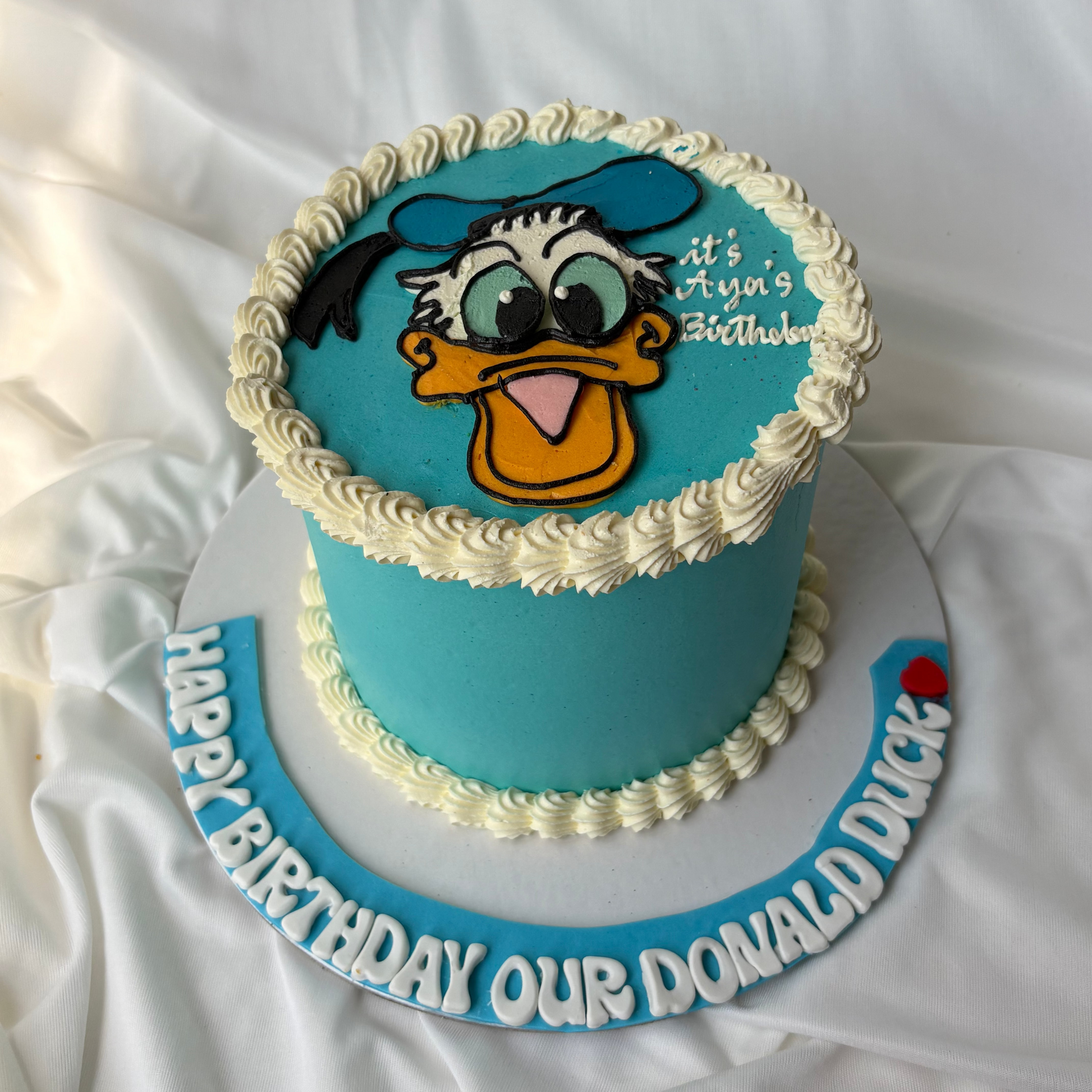 Blue birthday cake with Donald Duck face on a white background