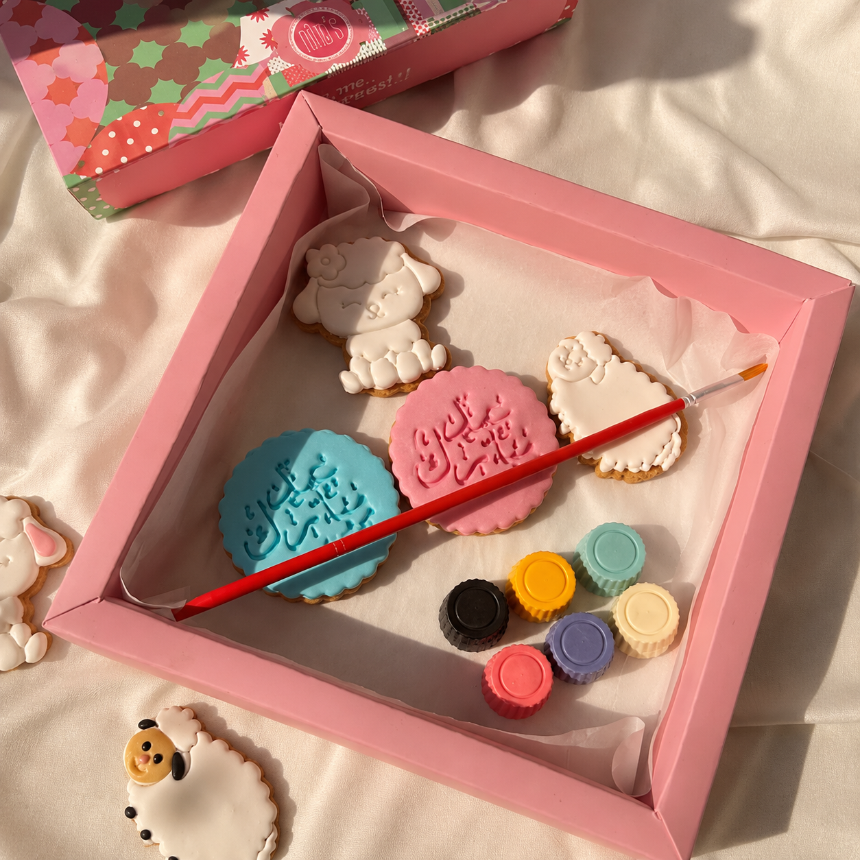 Decorative cookie set with paintbrush and color samples in a pink box.