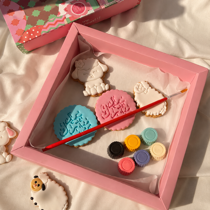 Decorative cookie set with paintbrush and color samples in a pink box.