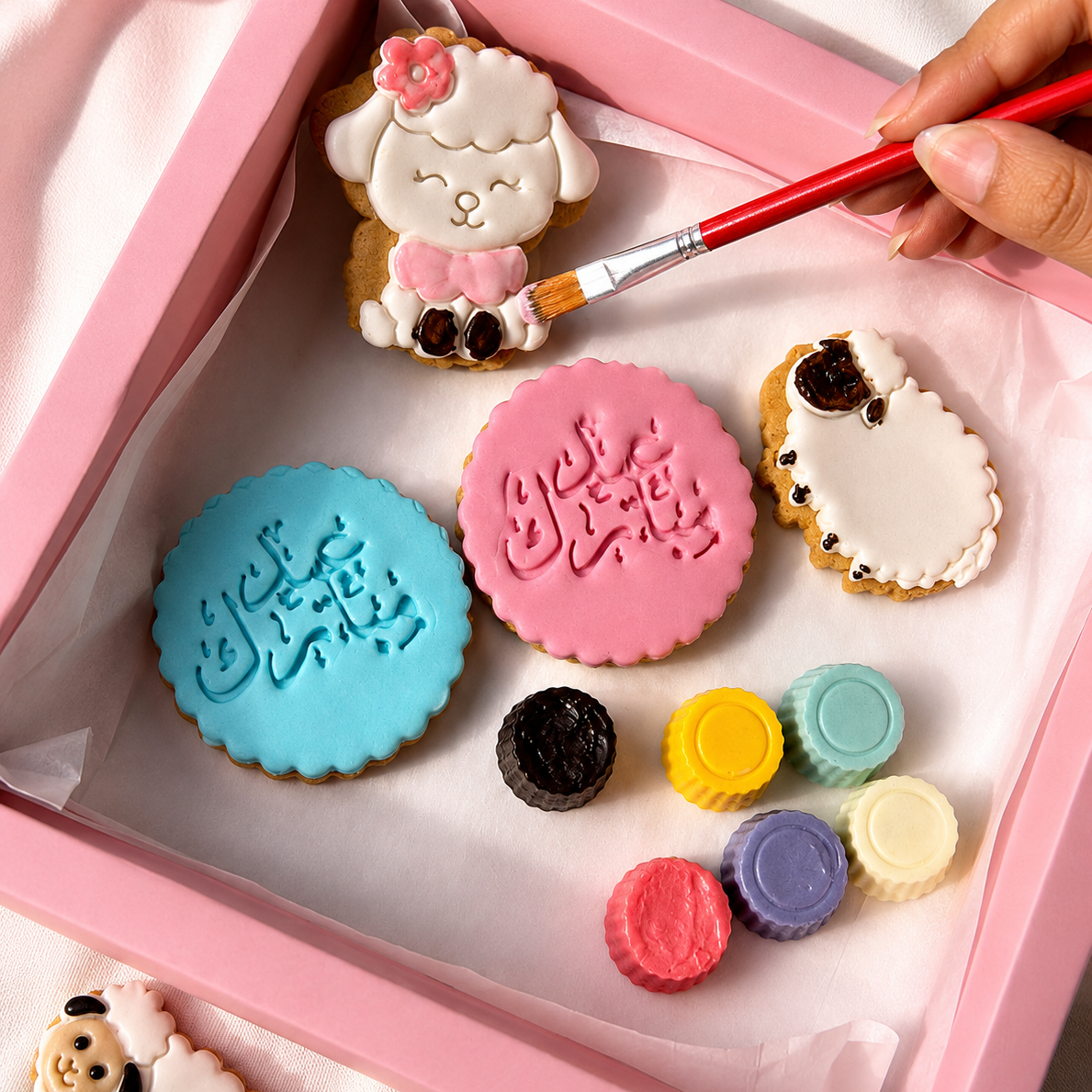 Decorative cookies with colorful icing and a brush in a pink box.