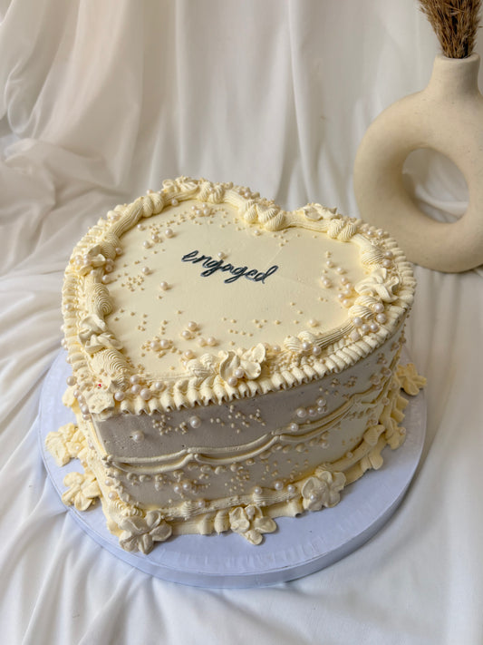 Decorative cake with 'engaged' text on a white background