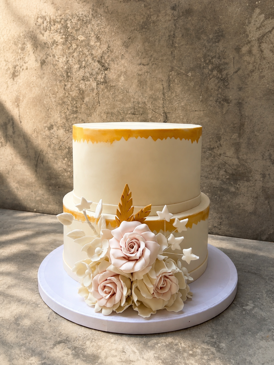 Two-tiered cake with floral decorations on a textured surface