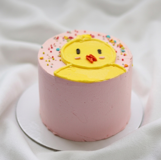 Little Chick Cake decorated with cute yellow chick face and colorful sprinkles on pastel pink frosting
