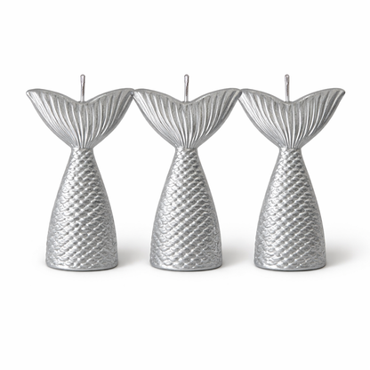 Three silver mermaid tail candles on a white background