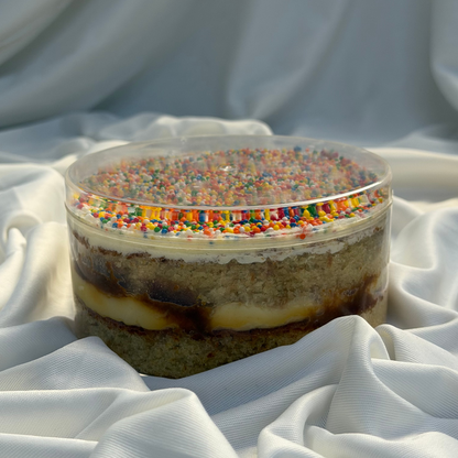 Layered dessert with colorful sprinkles on a white fabric background