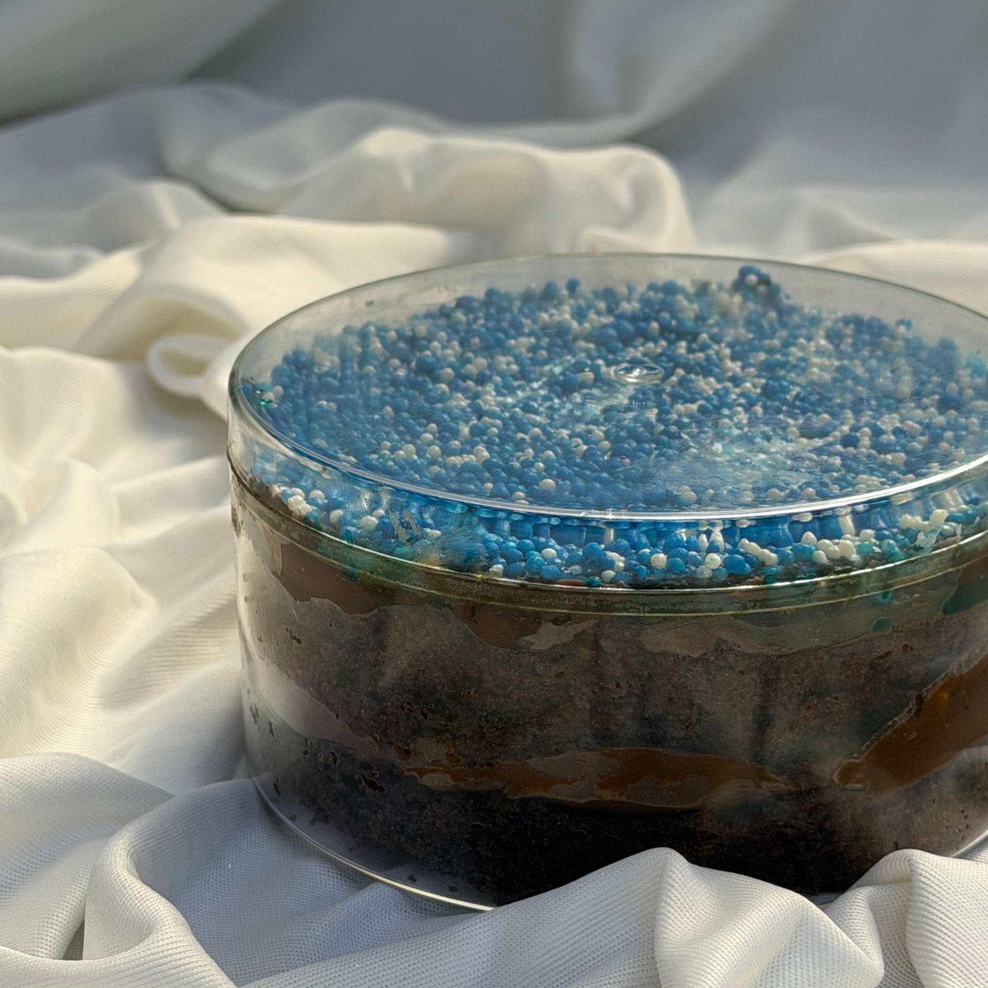 Glass bowl with blue and white beads on a white fabric background