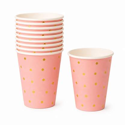 Stack of pink paper cups with gold polka dots on a white background