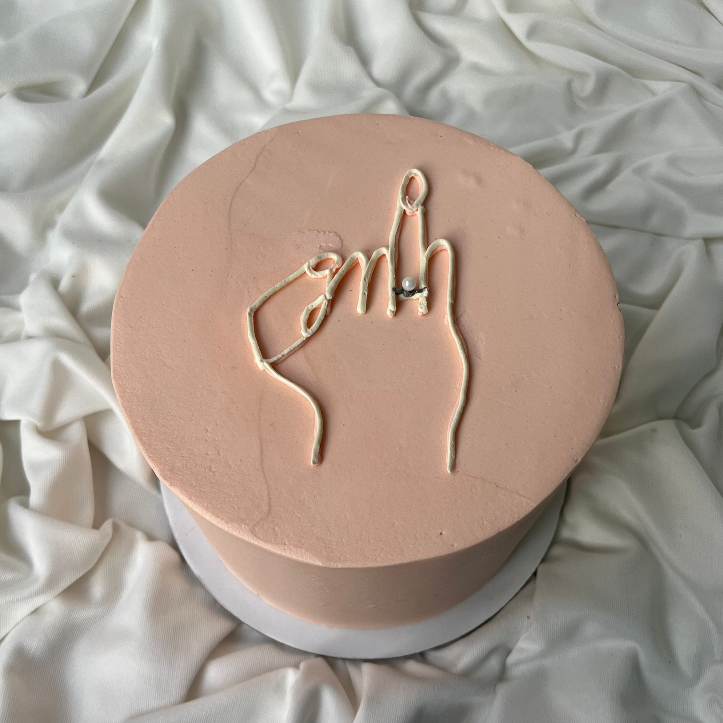 Round pink object with hand gesture design on a white fabric background