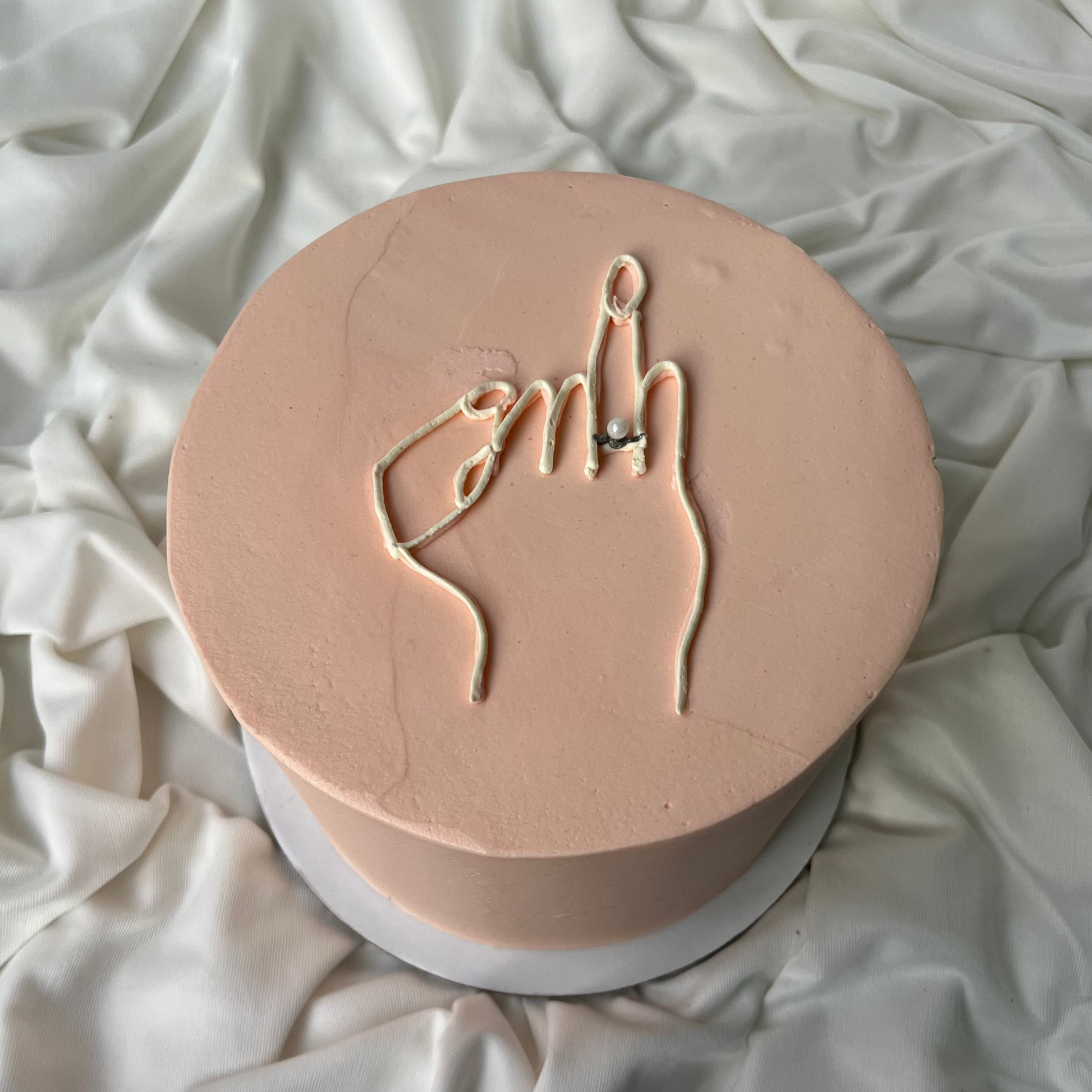 Round pink object with hand gesture design on a white fabric background
