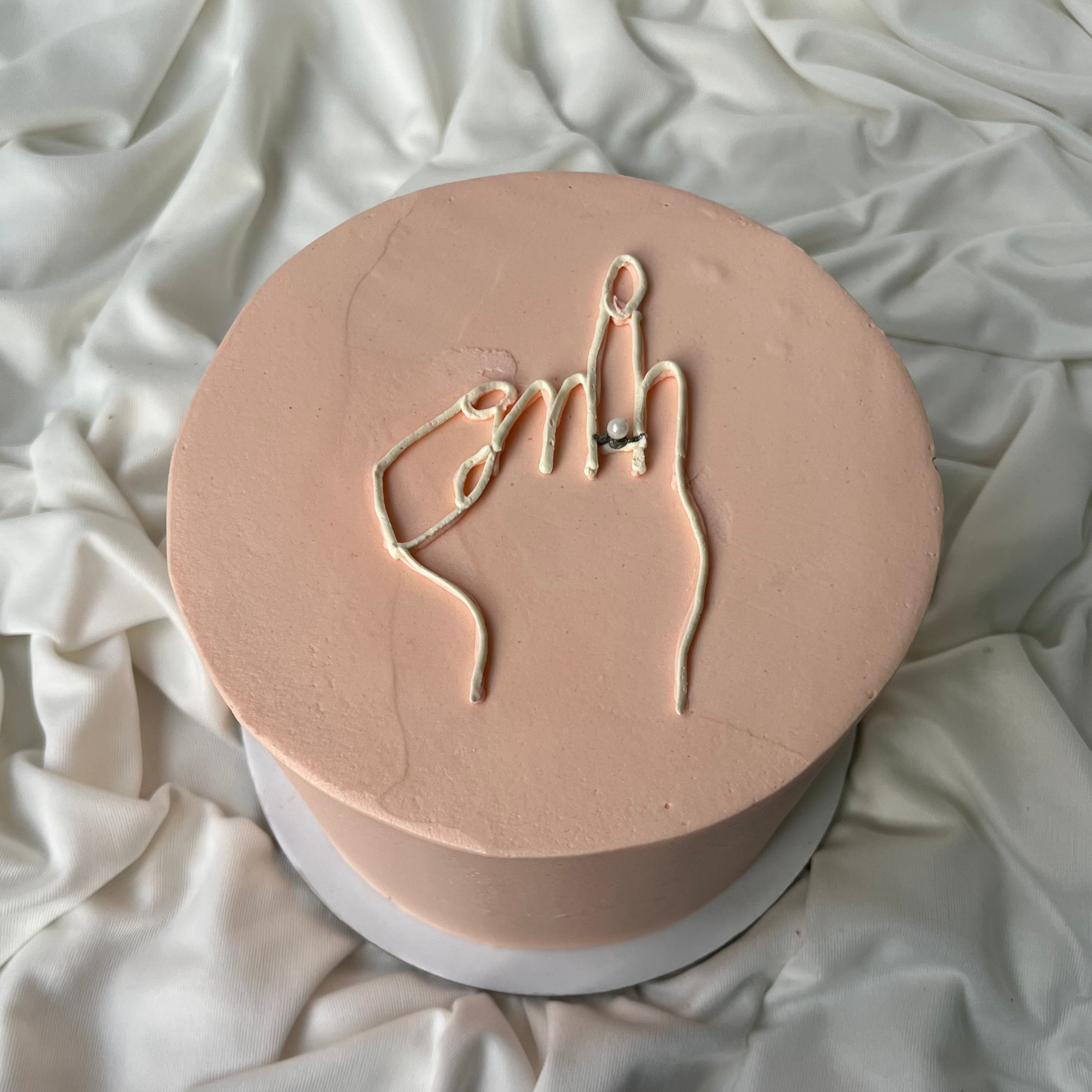 Round pink object with hand gesture design on a white fabric background