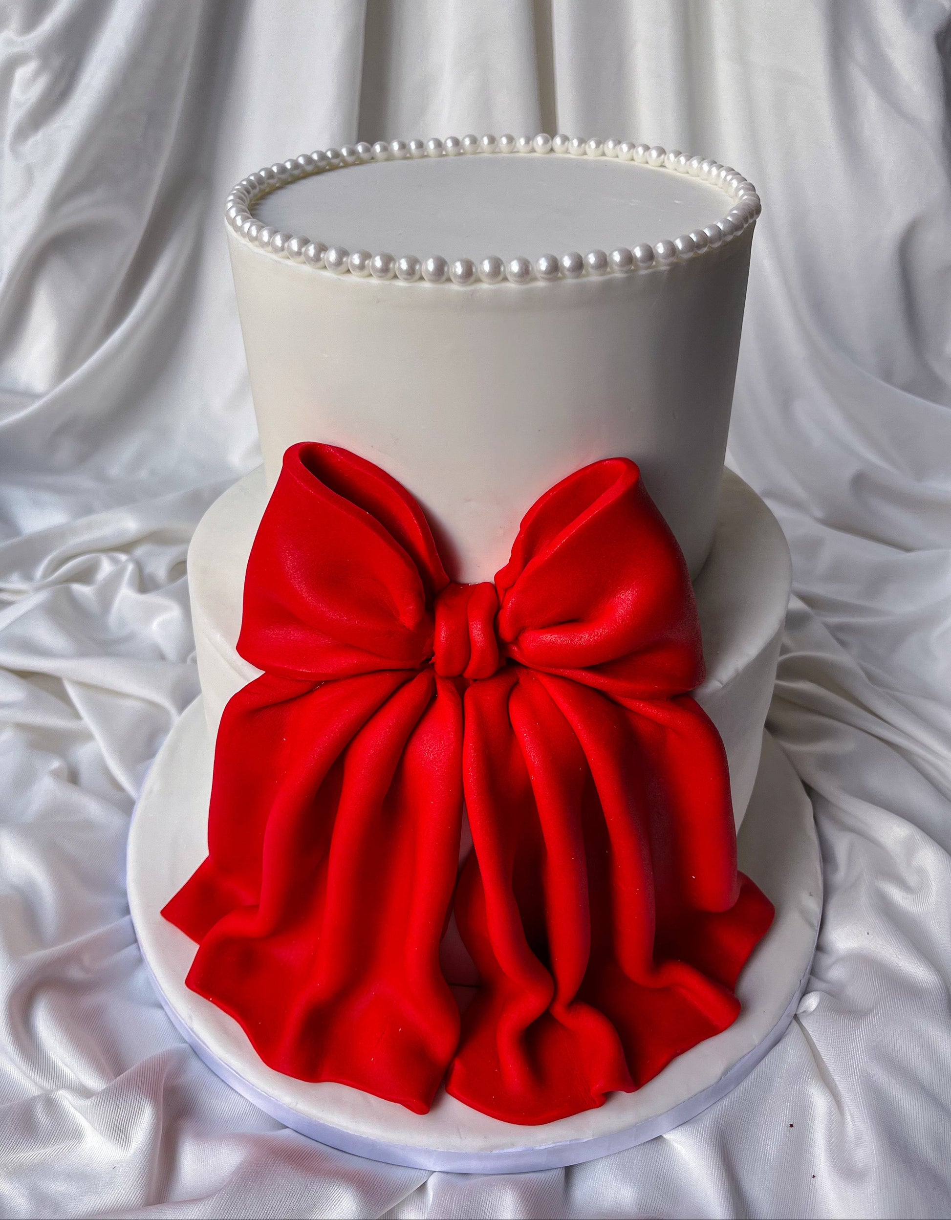 White cake with a large red bow on a white background