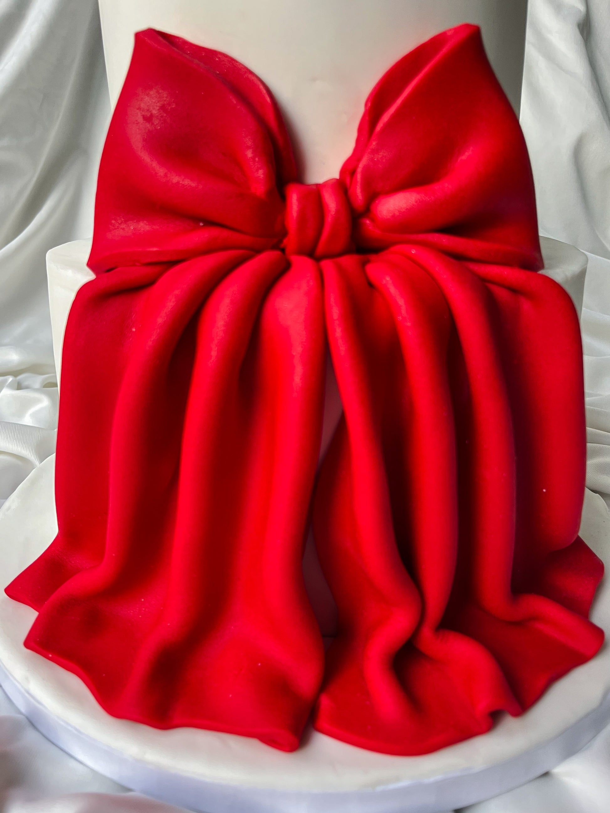 Red bow-shaped object on a white two tier cake