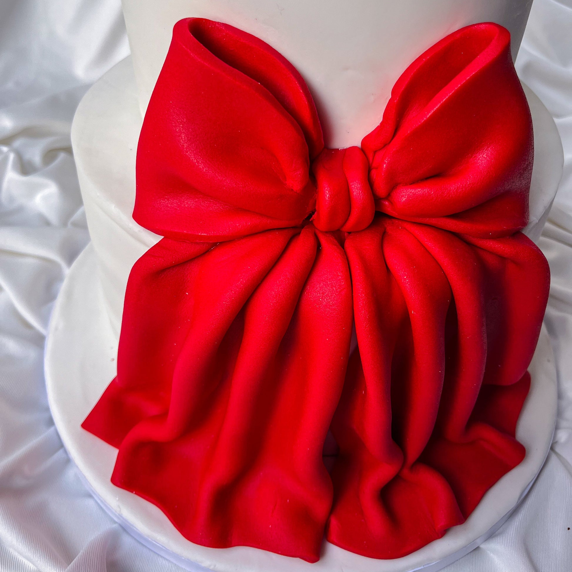 Red bow on a white cake against a white background