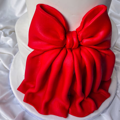 Red bow on a white cake against a white background