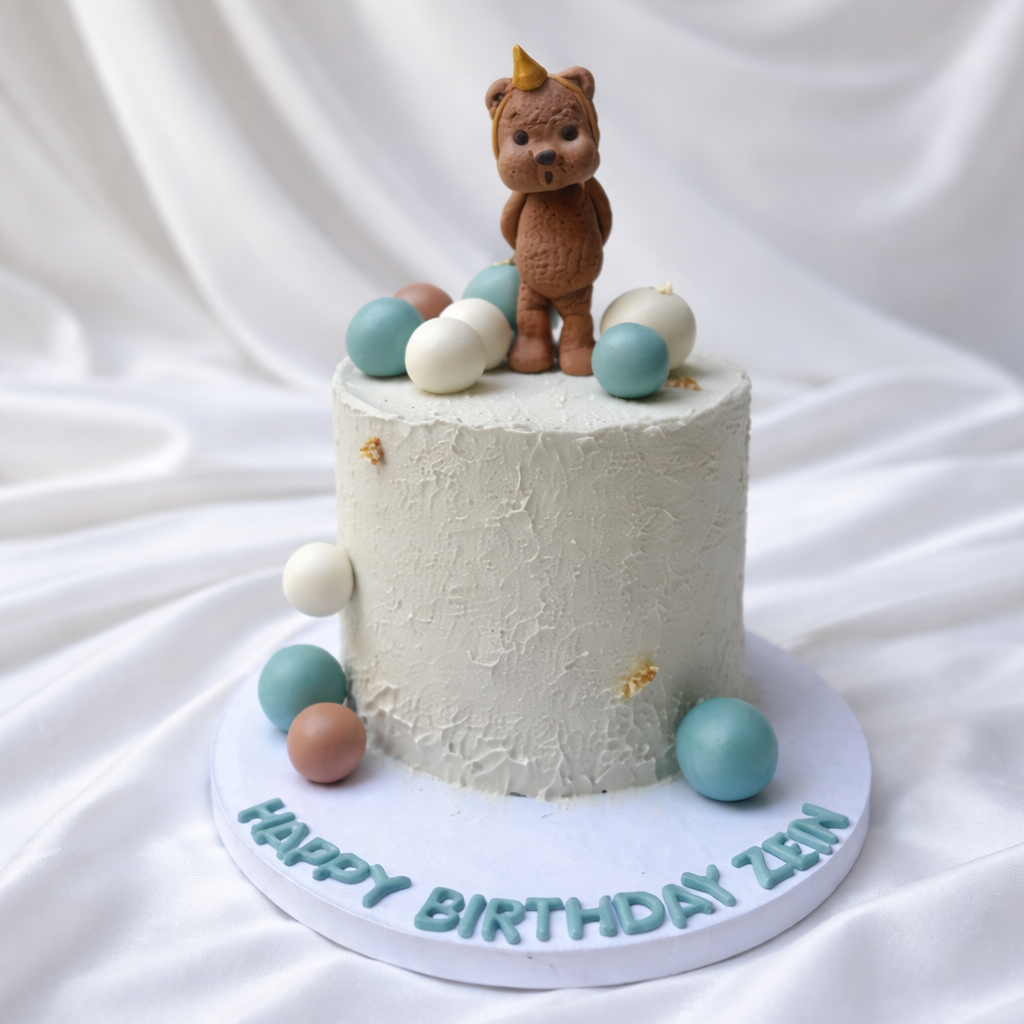 Small white cake with a teddy bear topper on a white background