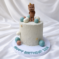 Small white cake with a teddy bear topper on a white background