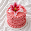Pink cake with a large pink flower on top against a white fabric background