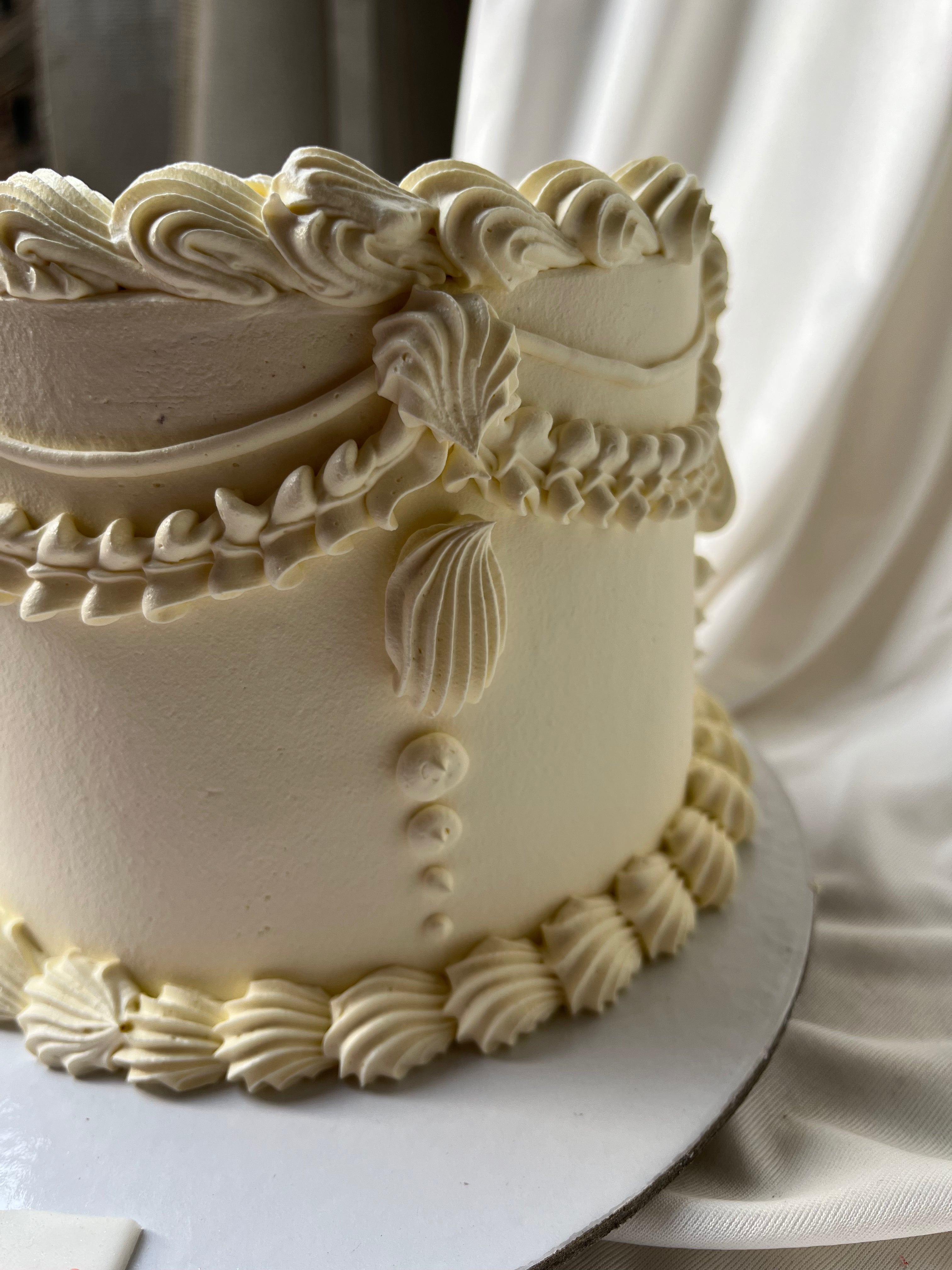 Decorative white cake with intricate designs on a white surface