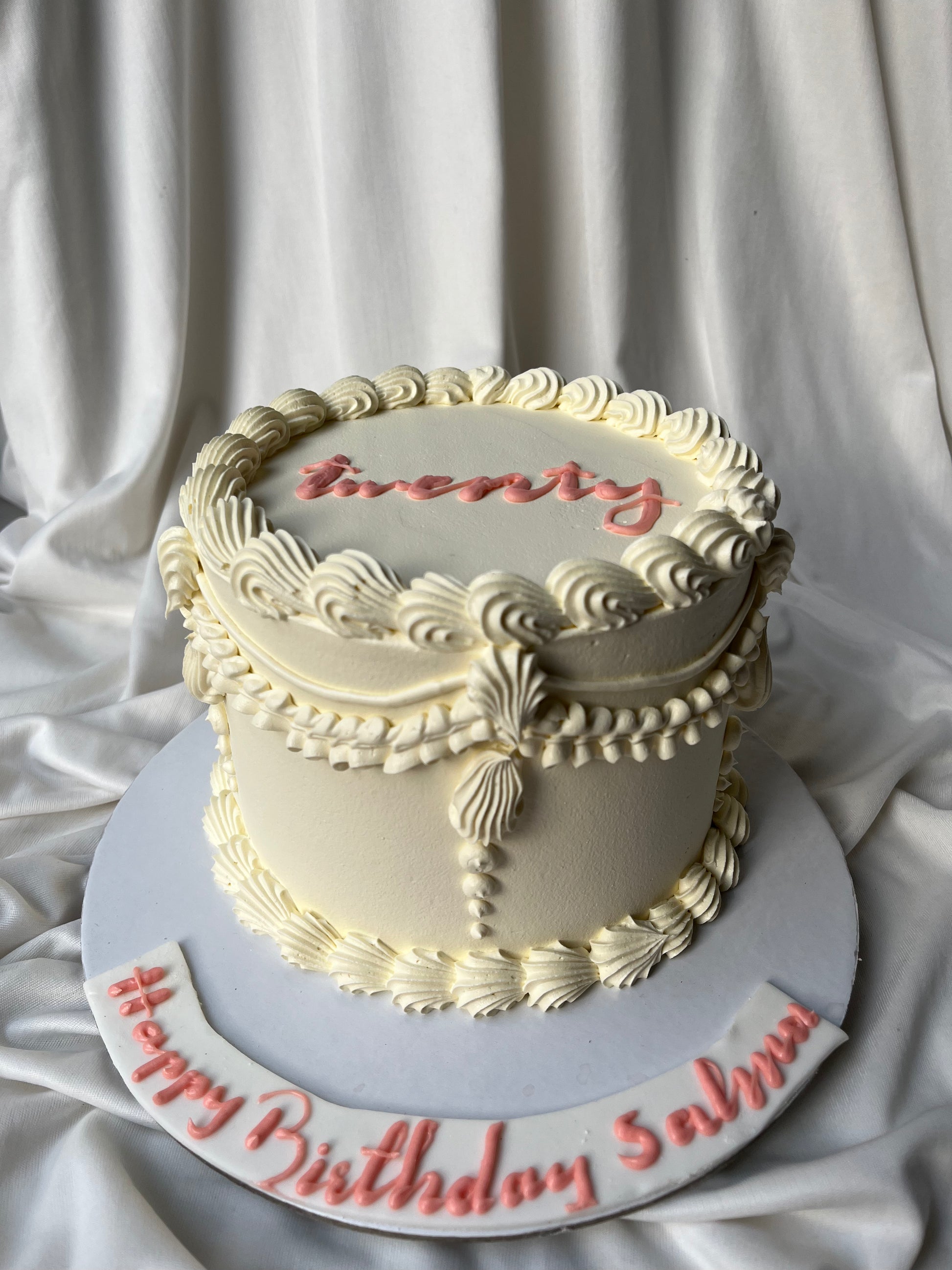 Decorative birthday cake with 'twenty' and 'Happy Birthday Salma' text on a white background