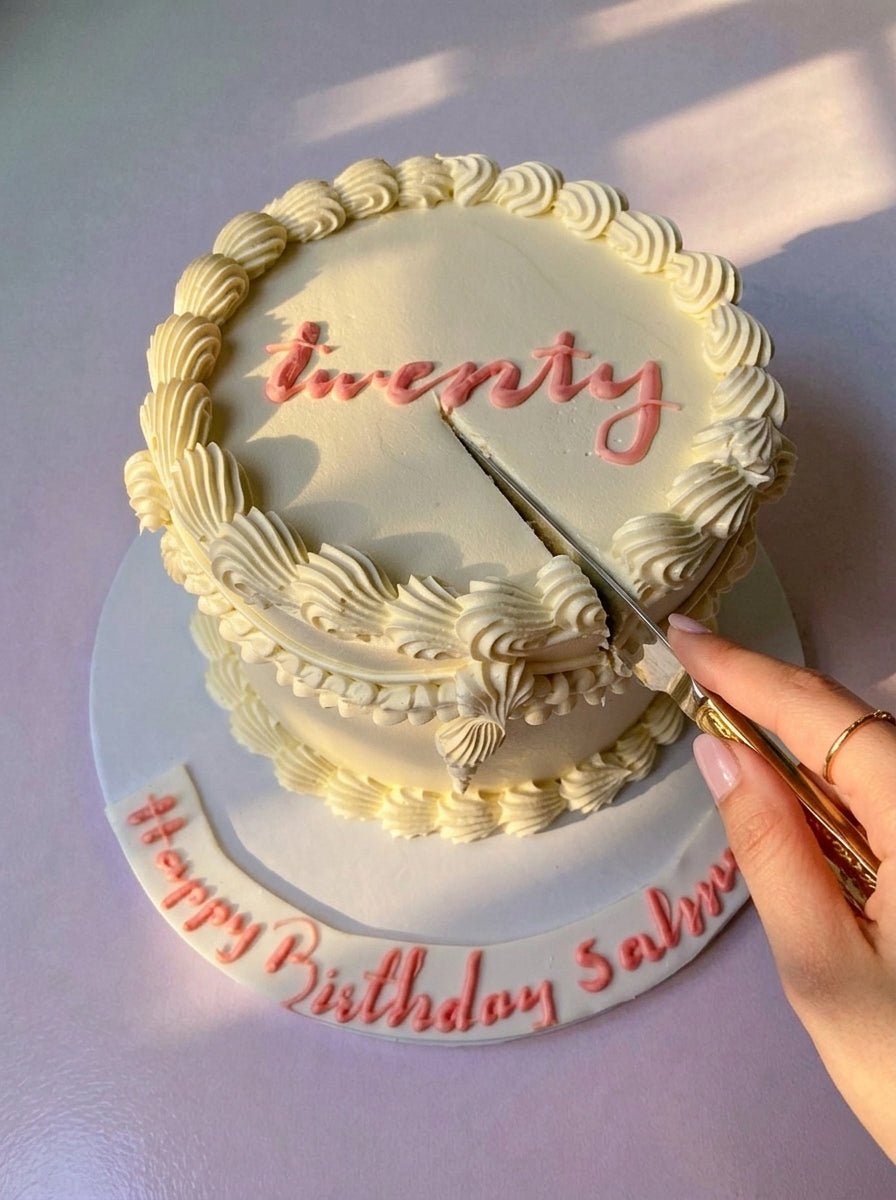 Cake with 'twenty' written on it, being cut with a knife.