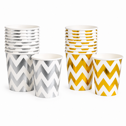 Gold and silver chevron party cups and matching plates arranged on a clean tabletop with festive confetti and striped paper straws.